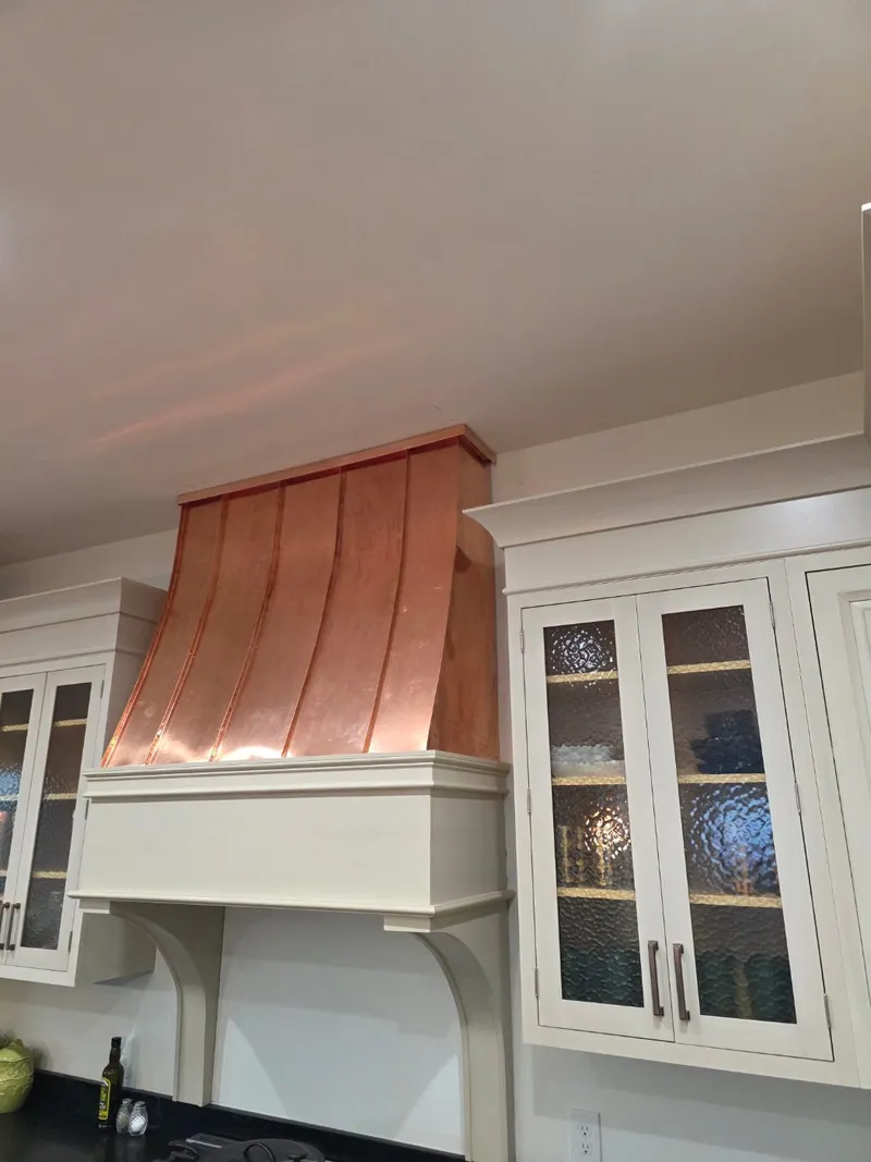Custom fabricated copper range hood installed in a kitchen