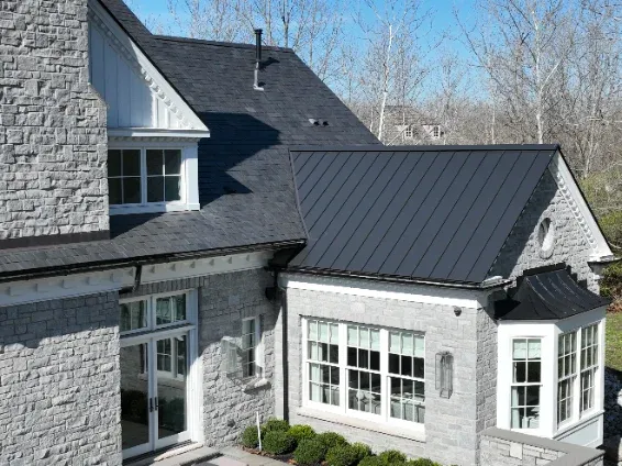 Dark standing seam metal roof panels on a stone house